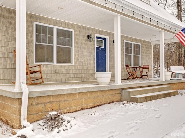 snow covered property entrance featuring a porch