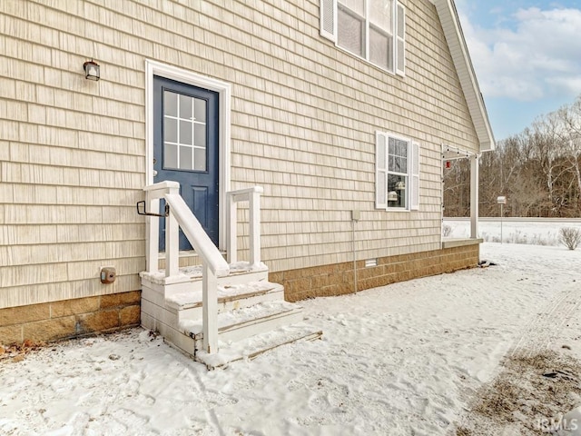 snow covered property entrance with crawl space