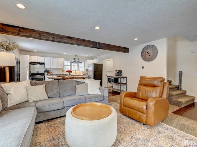 living area with beam ceiling, recessed lighting, light wood-style floors, a textured ceiling, and stairs