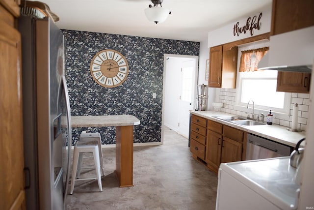 kitchen with brown cabinets, wallpapered walls, light countertops, and a sink