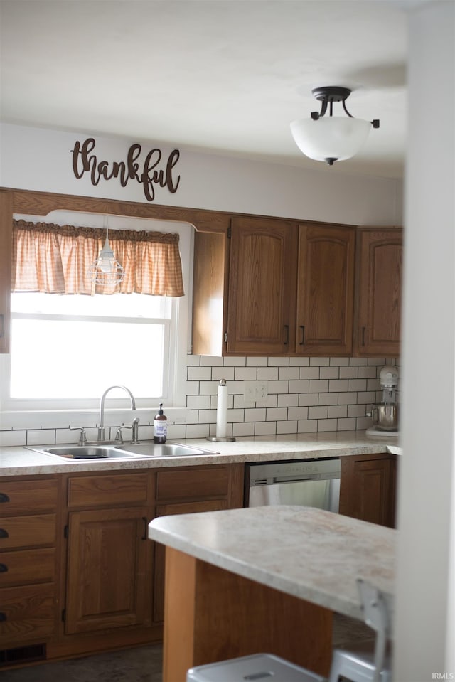 kitchen with a sink, light countertops, stainless steel dishwasher, and backsplash