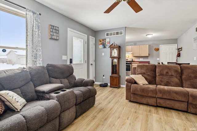 living room featuring baseboards, visible vents, ceiling fan, and light wood finished floors