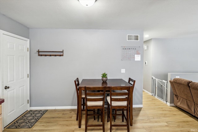 dining space featuring light wood-type flooring, visible vents, and baseboards