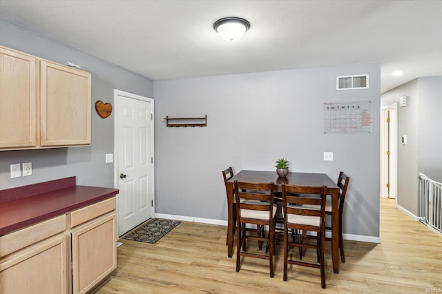 dining room featuring visible vents, light wood-style flooring, and baseboards