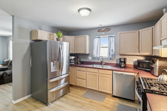 kitchen with appliances with stainless steel finishes, light wood-style floors, light brown cabinets, and a sink