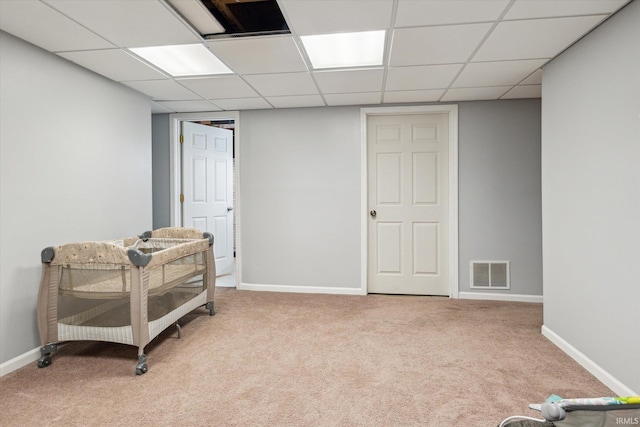 interior space featuring baseboards, a paneled ceiling, visible vents, and light colored carpet