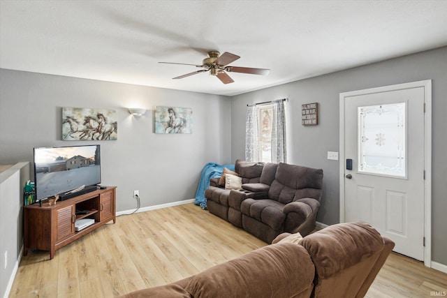 living area featuring baseboards, a ceiling fan, and light wood-style floors