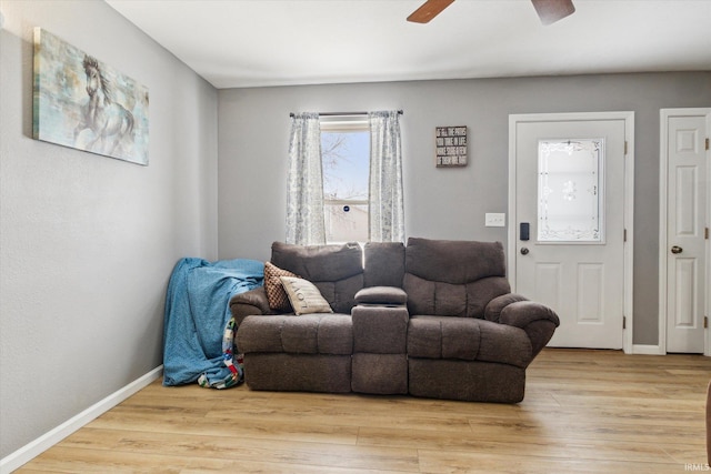 living room featuring baseboards, a ceiling fan, and light wood-style floors