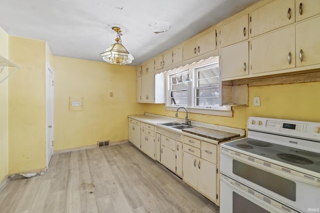 kitchen with range with two ovens, pendant lighting, light countertops, visible vents, and a sink