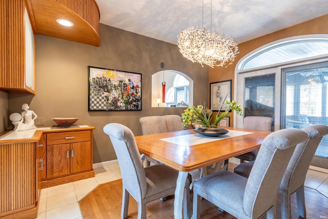 dining room with arched walkways, light tile patterned floors, baseboards, and an inviting chandelier