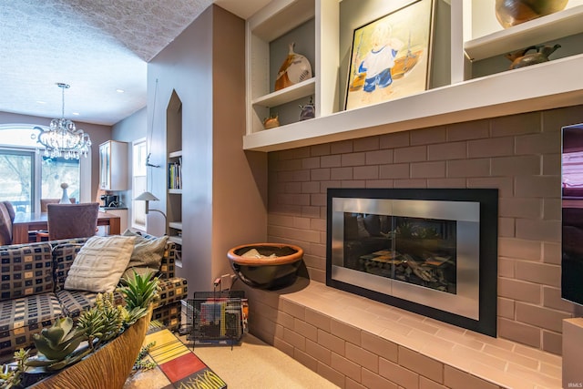 living room featuring an inviting chandelier, carpet flooring, a textured ceiling, a brick fireplace, and built in shelves