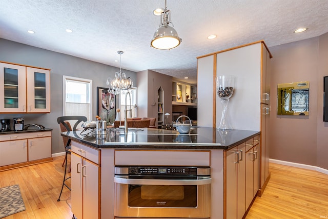 kitchen featuring dark countertops, oven, a kitchen island with sink, and a breakfast bar area