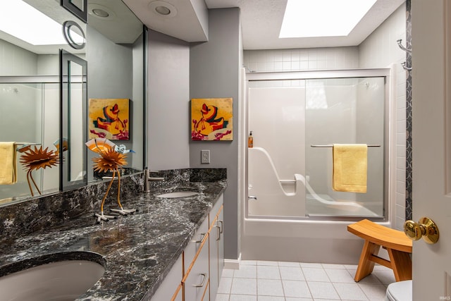 bathroom featuring double vanity, shower / bath combination with glass door, a sink, and tile patterned floors