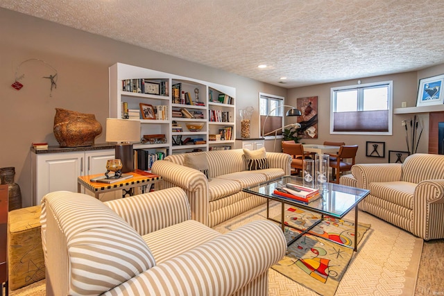 living area featuring built in shelves, light wood-style floors, and a textured ceiling