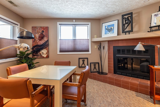 dining area featuring a textured ceiling, a fireplace, and visible vents