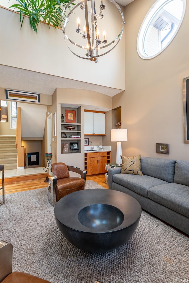 living room with light wood-style floors, a chandelier, stairway, and a high ceiling