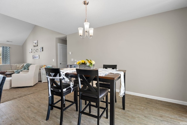 dining room with lofted ceiling, a notable chandelier, wood finished floors, and baseboards