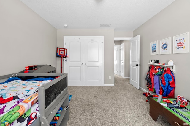 bedroom with visible vents, baseboards, light colored carpet, a textured ceiling, and a closet