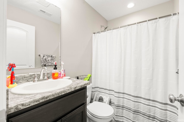 bathroom featuring curtained shower, visible vents, vanity, and toilet