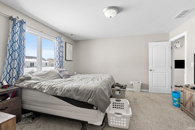 bedroom with a textured ceiling, carpet, visible vents, and baseboards