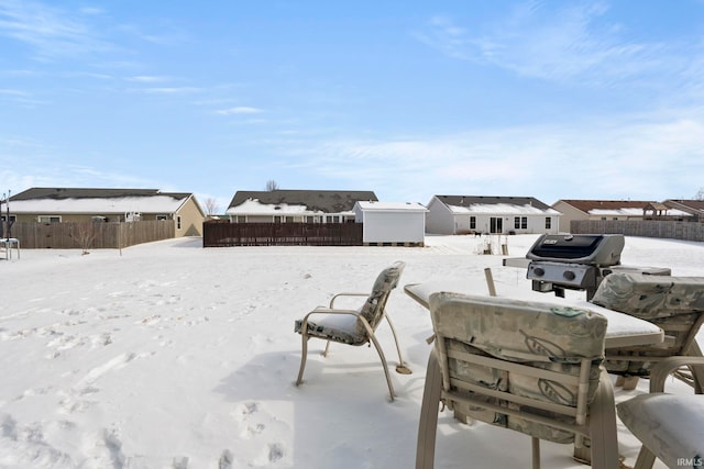 snowy yard with an outbuilding, a storage unit, and fence