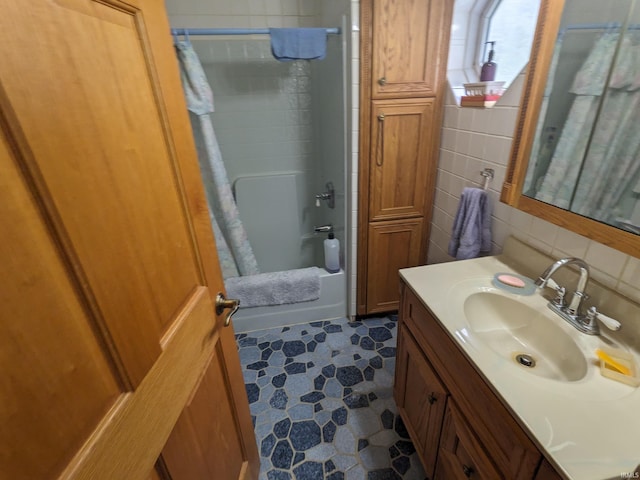 bathroom featuring tasteful backsplash, tile walls, shower / bath combination with curtain, and vanity