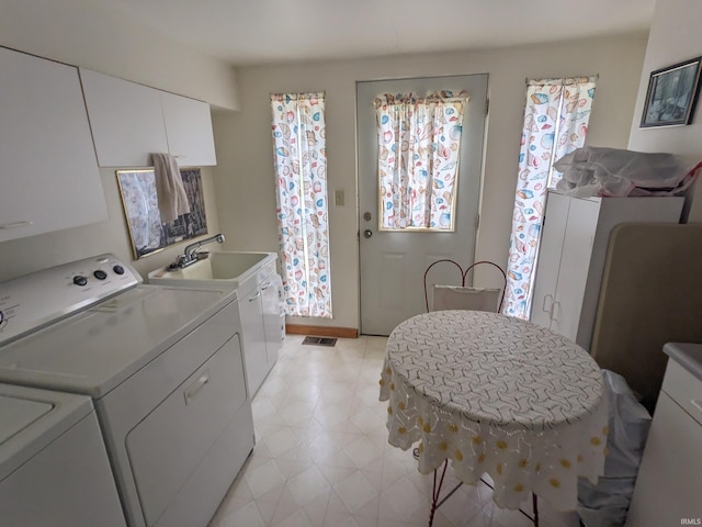 washroom featuring visible vents, a sink, cabinet space, and washer and dryer