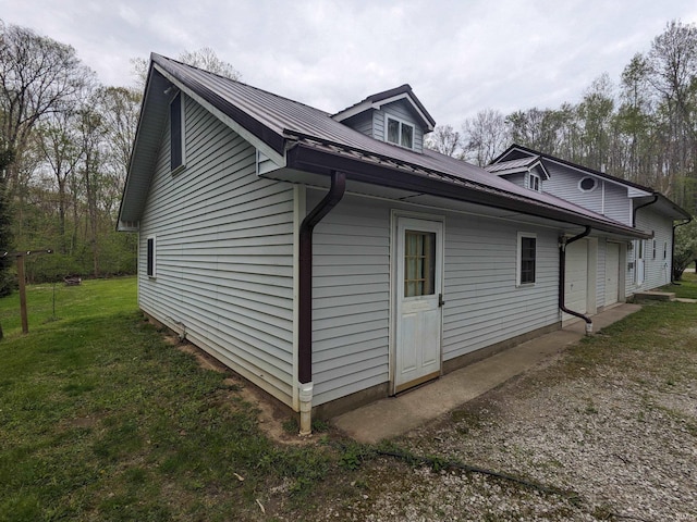 view of side of property featuring metal roof and a lawn