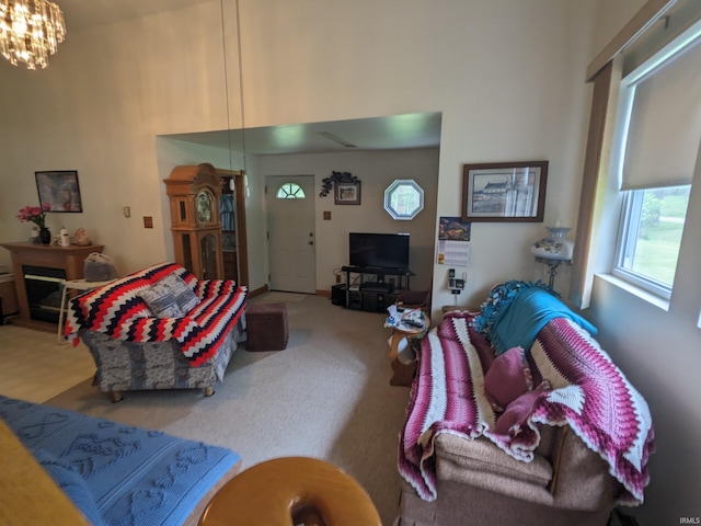 living room featuring carpet, a high ceiling, and an inviting chandelier