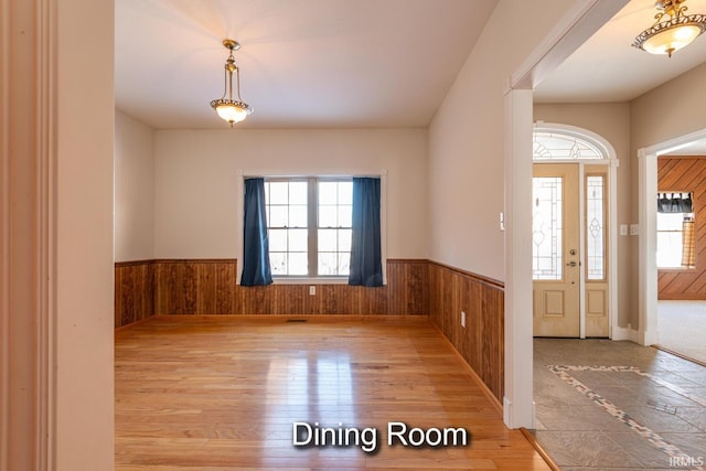 entryway with a wainscoted wall, wood walls, and wood finished floors