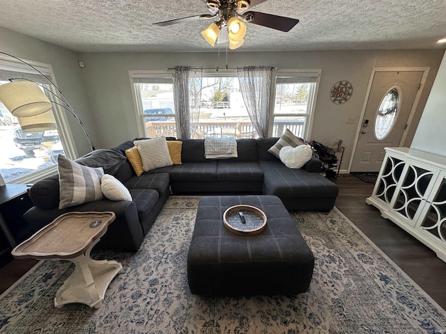 living area featuring dark wood-style flooring, plenty of natural light, a textured ceiling, and ceiling fan