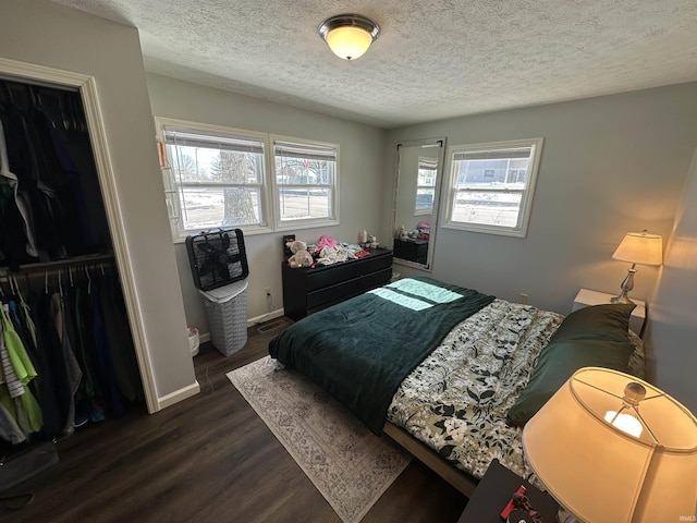 bedroom featuring a textured ceiling, dark wood-style flooring, a closet, and baseboards