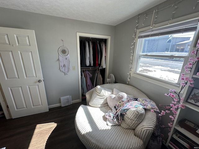 bedroom with dark wood-style floors, a textured ceiling, baseboards, and a closet