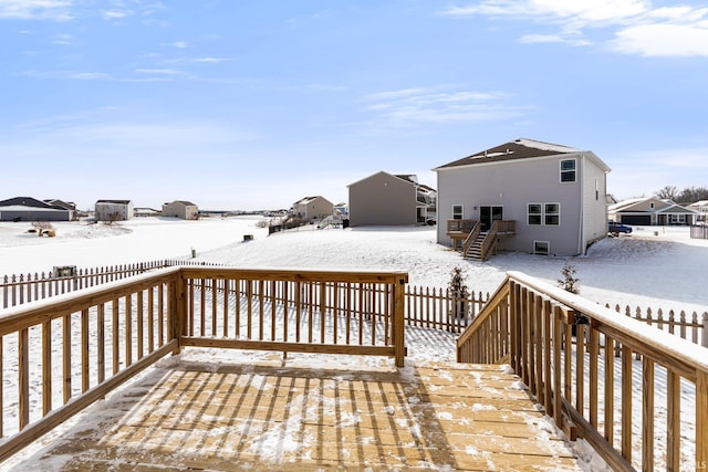 snow covered deck with a fenced backyard, a residential view, and stairway