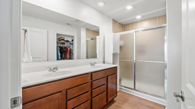 full bathroom featuring double vanity, a shower stall, a spacious closet, and a sink