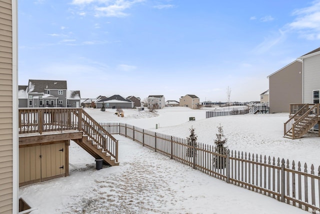 yard layered in snow with a residential view, fence, a deck, and stairs