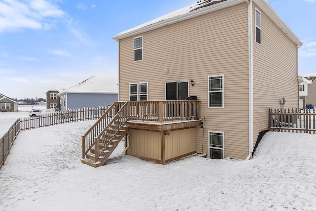 snow covered back of property with stairway, fence, and a wooden deck