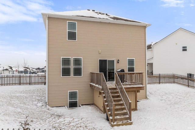 snow covered house with stairs, a deck, and fence