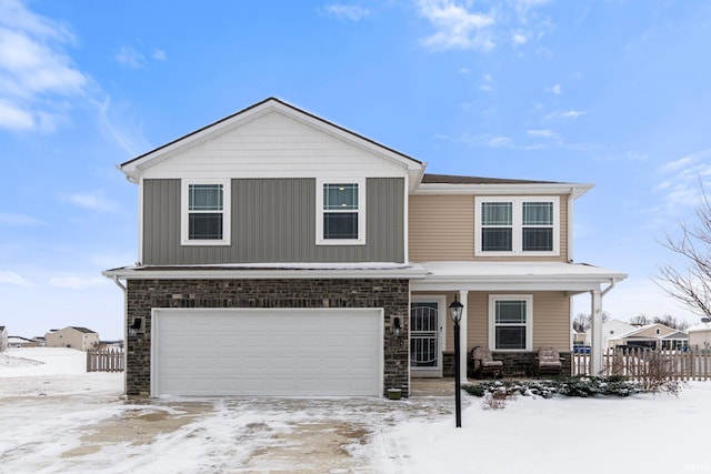 view of front of property with a garage, stone siding, covered porch, fence, and board and batten siding