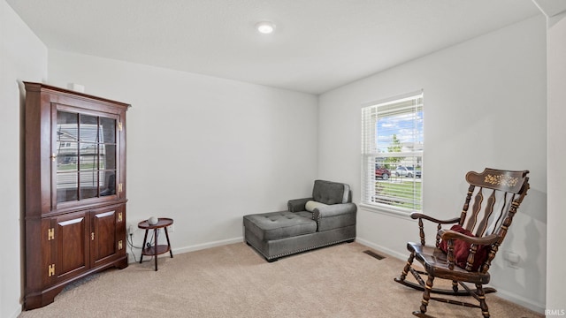 sitting room with baseboards, visible vents, and light colored carpet