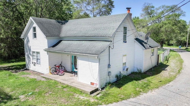 view of home's exterior with a yard, a shingled roof, a chimney, and cooling unit