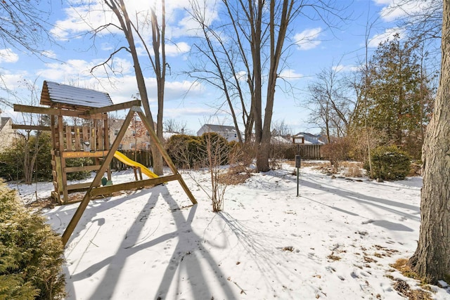 snowy yard featuring a playground