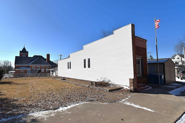 view of side of property featuring a storage shed, an outdoor structure, and fence