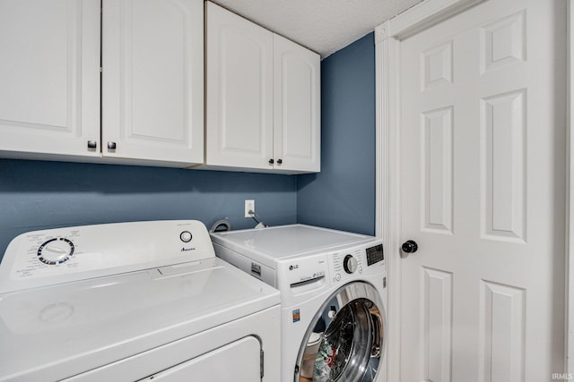 washroom featuring a textured ceiling, washer and clothes dryer, and cabinet space