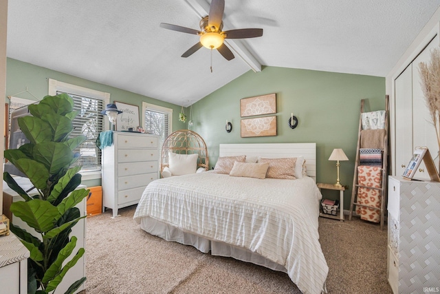 carpeted bedroom featuring a ceiling fan, vaulted ceiling with beams, and a textured ceiling