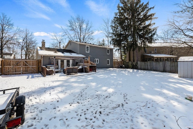 snow covered rear of property featuring a chimney and a fenced backyard