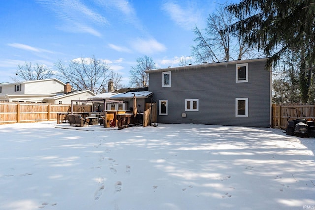 snow covered back of property with a gazebo and a fenced backyard