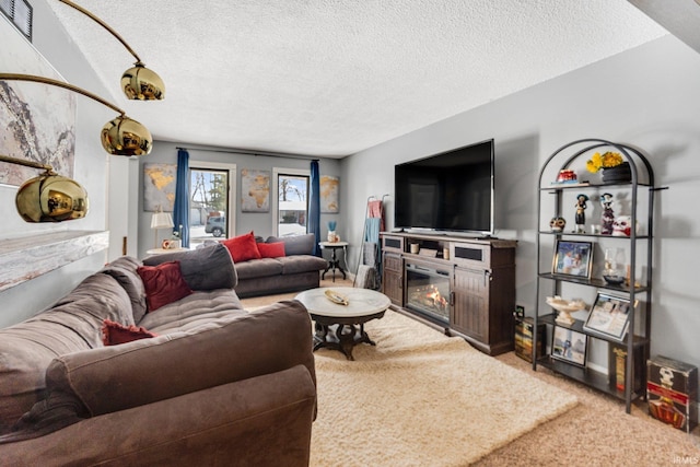 living room featuring a textured ceiling, carpet, and a glass covered fireplace