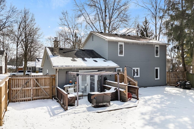 snow covered rear of property with a garage, a gate, and fence