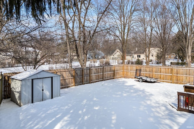 snowy yard with a fenced backyard, a residential view, a storage unit, and an outdoor structure